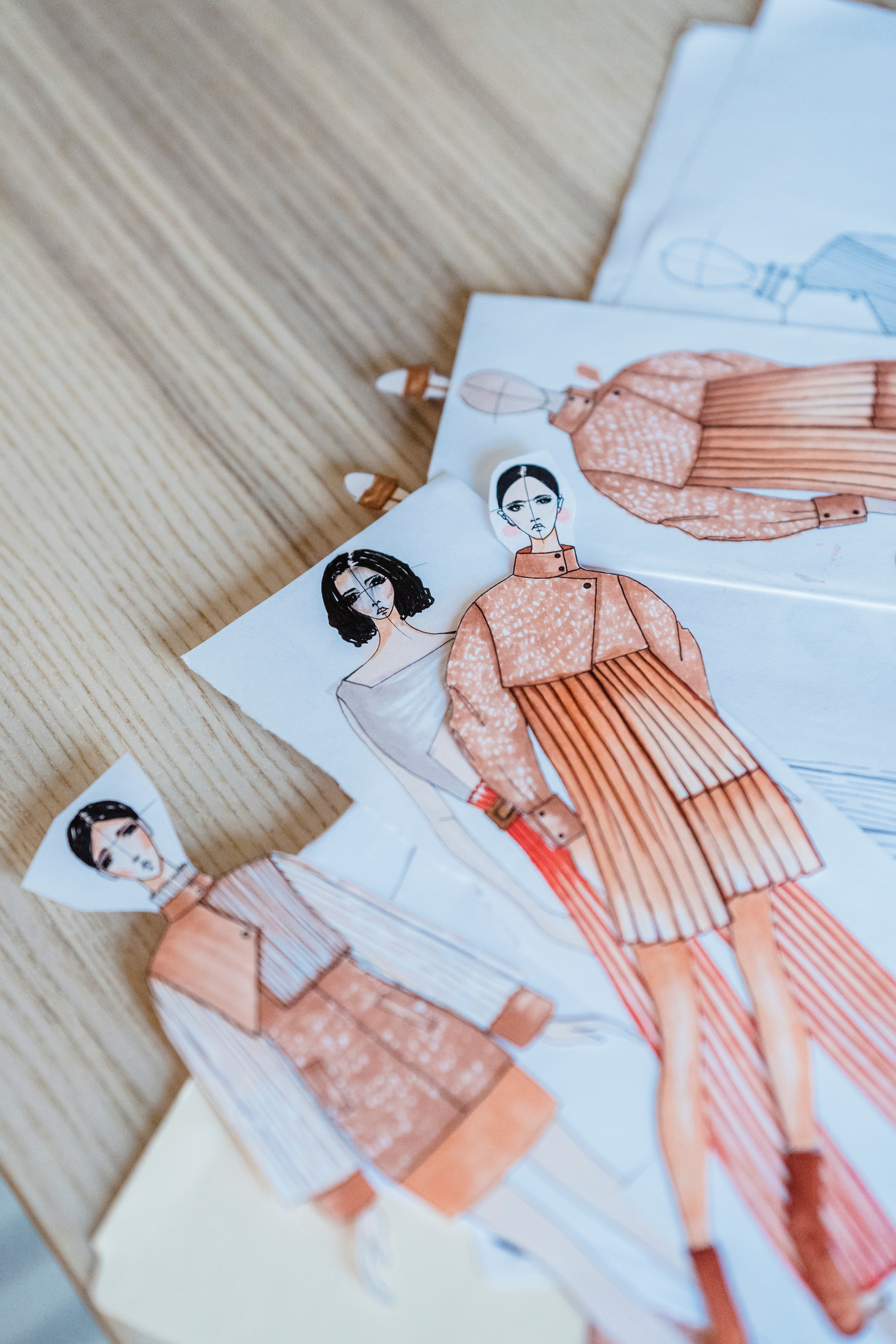 Collection of drawn fashion sketches on wooden table