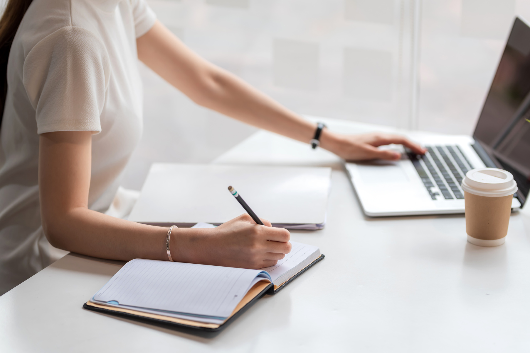 Close up of Woman Taking Notes and Using Laptop at the Home.